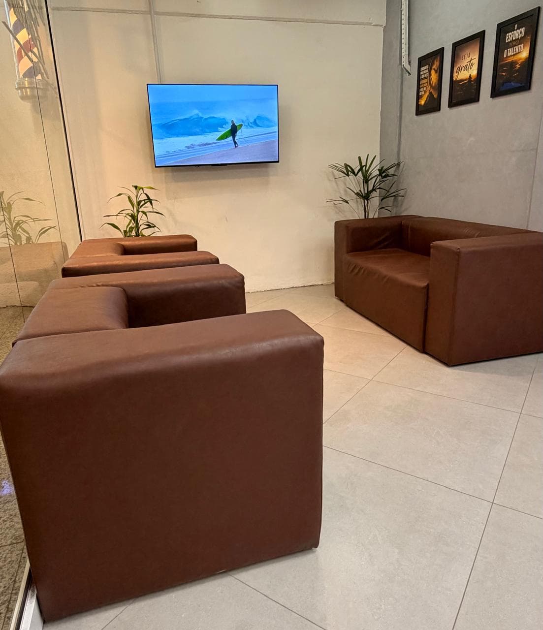 Poltronas de couro da sala de espera da Eleve, de frente para a televisão