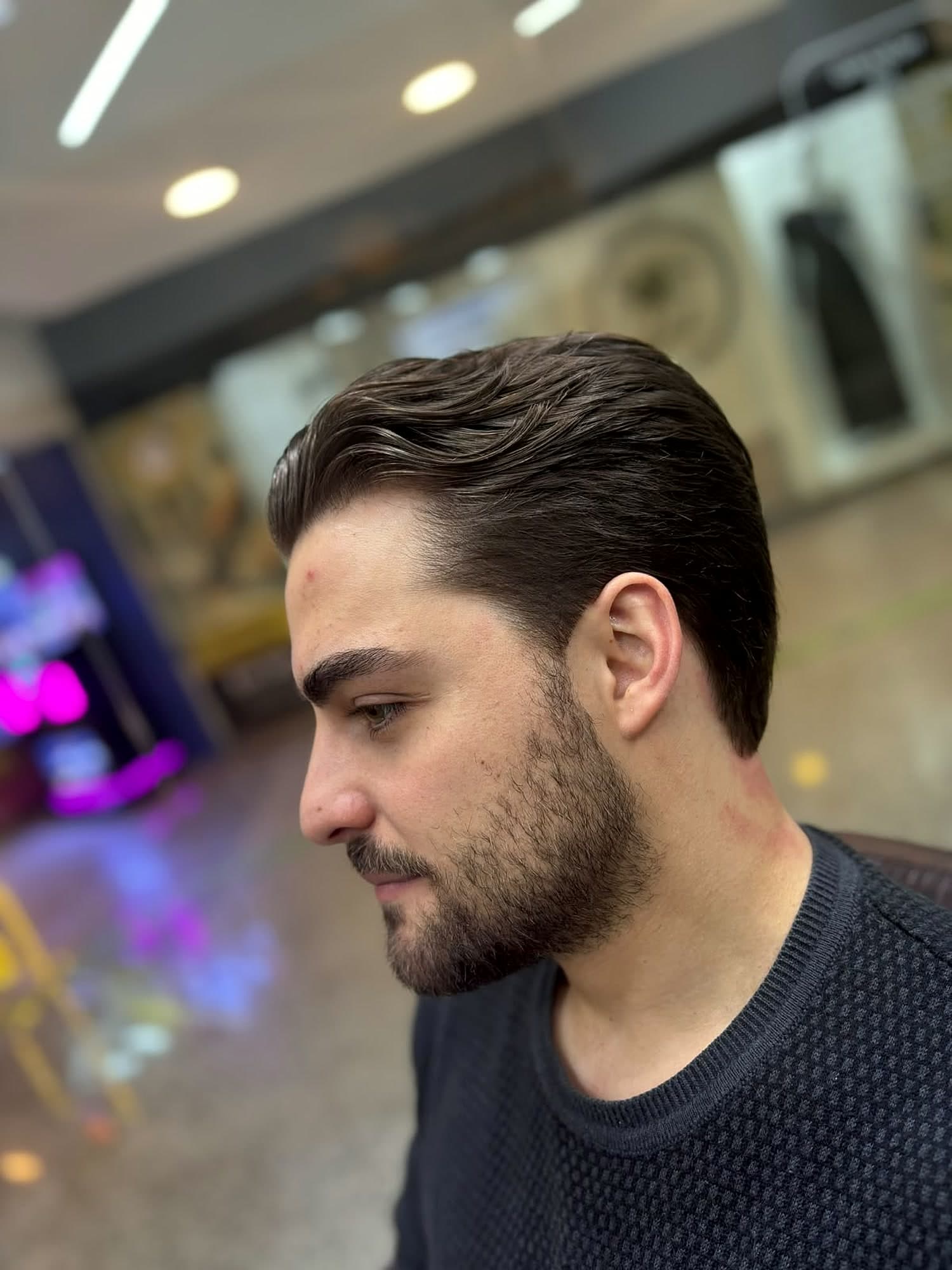Corte social penteado para trás com barba curta alinhada, feito na Eleve Barbearia